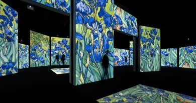 A dark room with multiple screens showing projections of Vincent Van Gogh's Irises painting